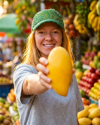 Fien van Fijn Fruit op de markt met een mango in haar hand