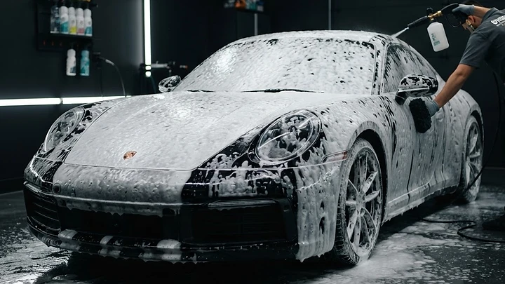Thick pH-neutral snow foam blanketing dark paint during a hand wash