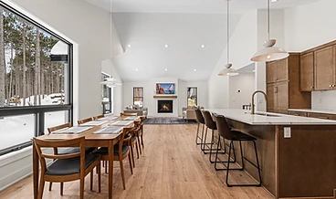 Open kitchen, dining, and living room with a fireplace and snow-view windows