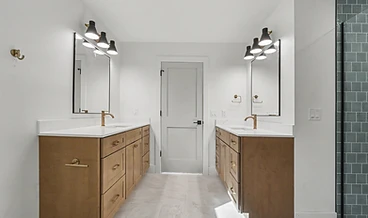 Dual-vanity bathroom with wood cabinetry, brass fixtures, and a green-tiled walk-in shower