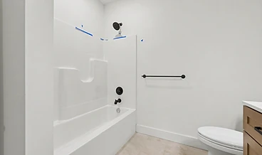Bathroom with a white tub surround, matte black hardware, and a wood vanity corner