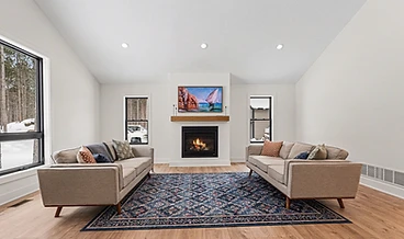 Living room with vaulted ceiling, fireplace, and patterned rug