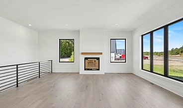Great room with a fireplace, light wood mantel, and floor-to-ceiling windows