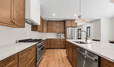 Kitchen with shaker cabinetry, white quartz island, and a brass faucet