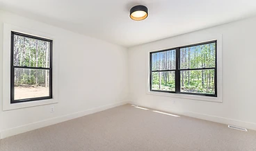Sunlit bedroom with forest-facing windows