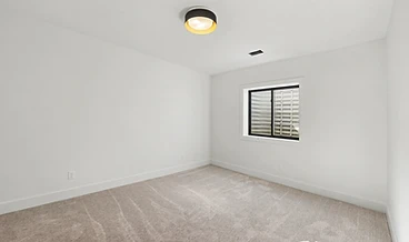 Basement room with a circular flush-mount light and a black-framed window well
