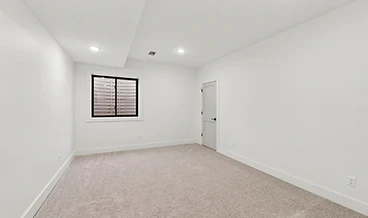 Basement room with beige carpet, a black-framed window, and a dropped ceiling