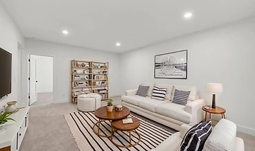 Virtually staged basement living area with a striped rug, cream sofa, and wall-mounted TV