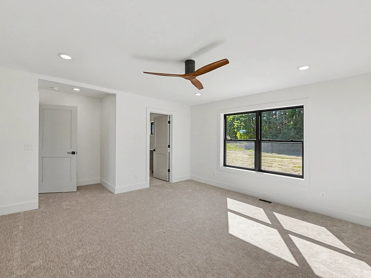 Halmstad bedroom with black-framed window, ceiling fan, and light carpet