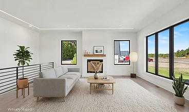 Virtually staged living room with a grey sofa, fireplace, and a wall of windows