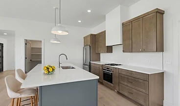 Virtually staged kitchen with a slate island, wood cabinetry, and pendant lights