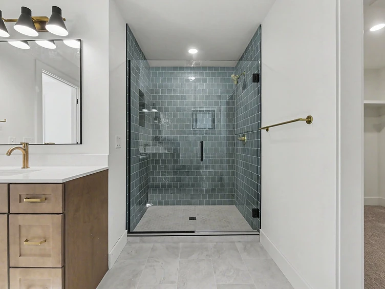 Halmstad primary bathroom with dark wood vanity, brushed gold fixtures, and glass shower