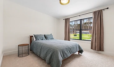 Bedroom with sage bedding and forest view