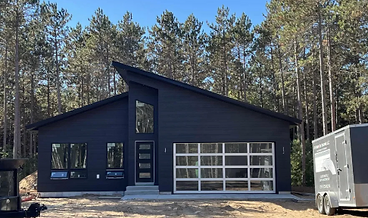 Modern single-story home with dark siding and a glass garage door