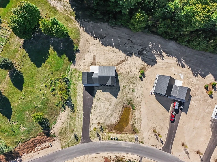Aerial drone view of the Halmstad home with curved driveway and metal roof