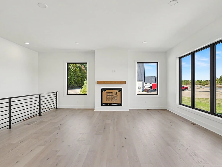 Halmstad living area with fireplace, black-framed windows, and light hardwood floors