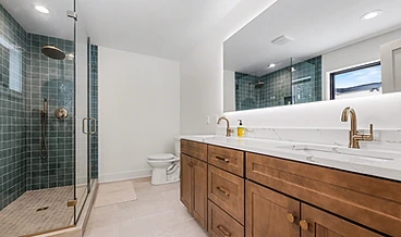 Dual-vanity bathroom with LED mirror and teal walk-in shower