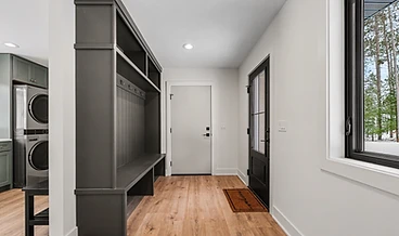 Built-in mudroom with charcoal lockers, bench, and coat hooks beside the laundry