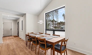 Dining area with a floor-to-ceiling window opening onto the winter woods