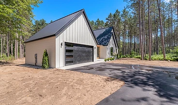 Modern farmhouse with white board-and-batten siding, a black garage door, and a wood entry accent