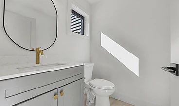 Powder room with a grey vanity, round black-framed mirror, and a brushed gold faucet