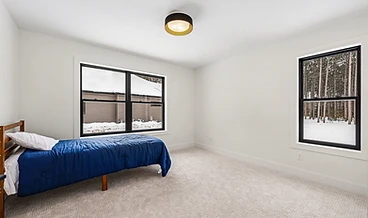 Bedroom with black-framed windows overlooking the pines