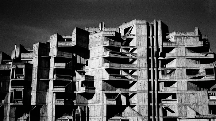 Brutalist concrete facade with angular shadows casting geometric patterns