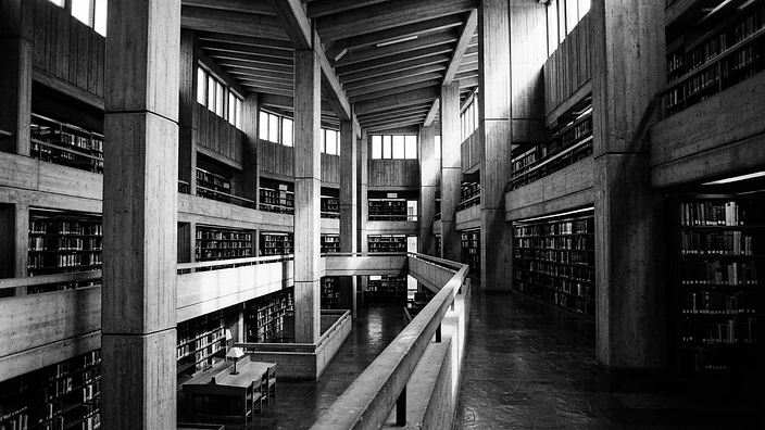 Interior of a brutalist library with dramatic shadows and towering columns