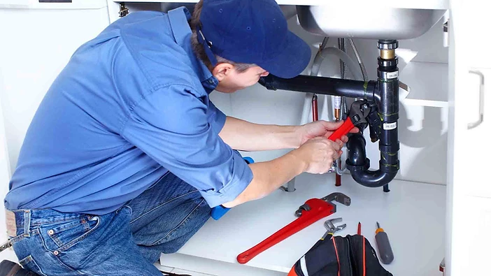 Arizona plumber repairing a pipe under a kitchen sink