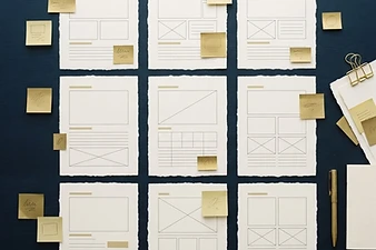 Storyboard of ivory paper layouts and gold sticky notes