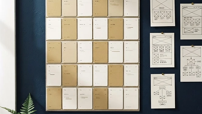 Wall planner with weeks blocked out beside website wireframe sketches