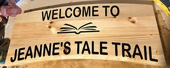Front of the Jeanne's Tale Trail sign — WELCOME TO with an open book