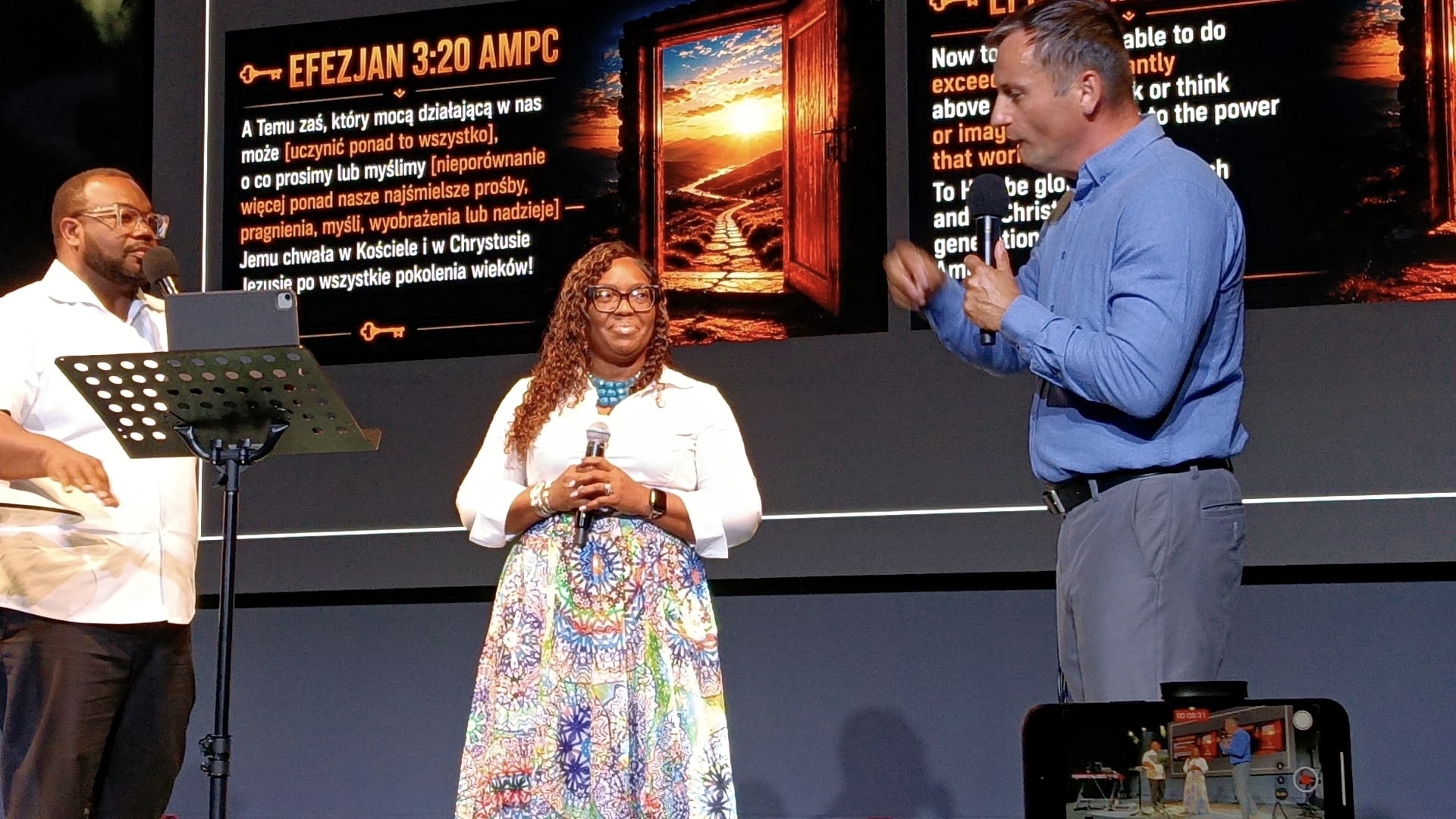 Three people on stage during a conference in Poland