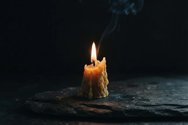 A single lit candle on a dark stone table