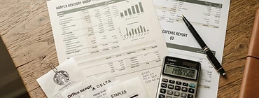 Printed financial statements and receipts spread across a desk with a calculator