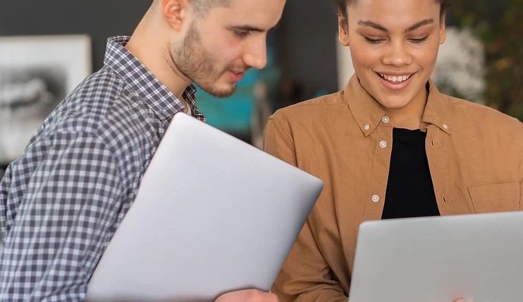 Two colleagues reviewing work on laptops