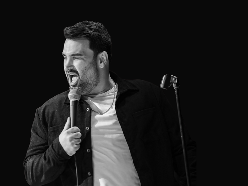 Michael Pasvar on stage performing stand-up comedy