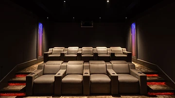 Monolith front row of structured recliners in a low-lit cinema