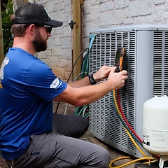 Technician crouching with a diagnostic meter on a grey Daikin AC condenser
