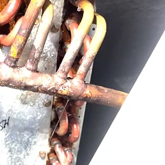 Corroded evaporator coil with an active refrigerant leak before repair