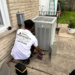 Alltech HVAC technician in uniform servicing an outdoor condenser