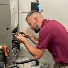 Alltech HVAC technician using a screwdriver and clamp meter during a furnace service call