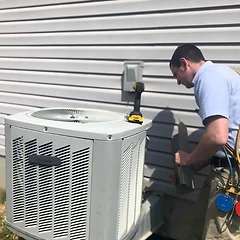 HVAC technician removing a panel from an outdoor AC condenser against vinyl siding