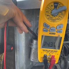 Yellow Fieldpiece multimeter reading 24.3 volts during an HVAC electrical test