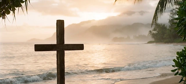 A simple wooden cross on a quiet Hawaiian shoreline at sunrise, gentle waves and warm golden light