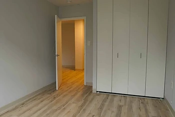 Renovated apartment bedroom with new plank flooring and closet doors, PACT Renaissance Collaborative