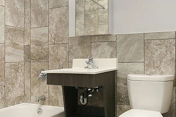 Renovated apartment bathroom with full tile surround, wall-mounted vanity and new fixtures, PACT Renaissance Collaborative
