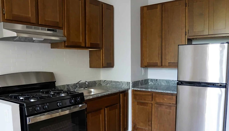 Renovated apartment kitchen with new wood cabinetry, stone countertop, subway tile backsplash and stainless appliances at 99 Fort Washington Avenue, Washington Heights