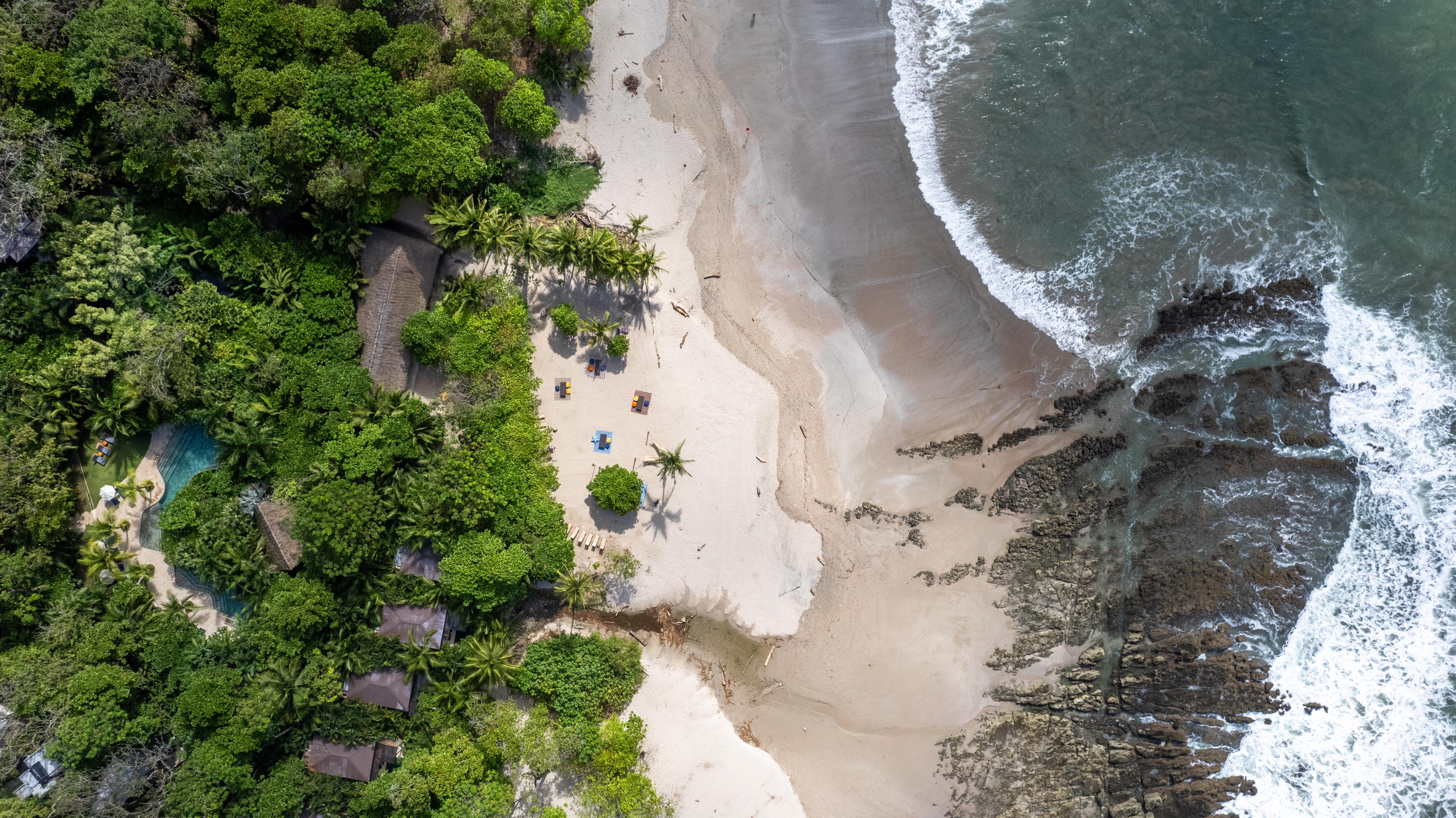 Aerial view of a beachfront resort surrounded by rainforest and ocean