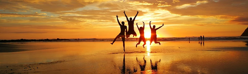 Friends jumping on the beach at sunset